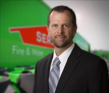 General Manager in suit in front of a SERVPRO themed background